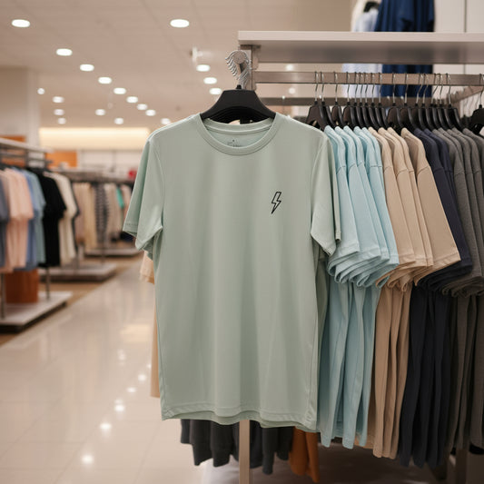 Light green t-shirt with a small logo on a hanger in a clothing store.