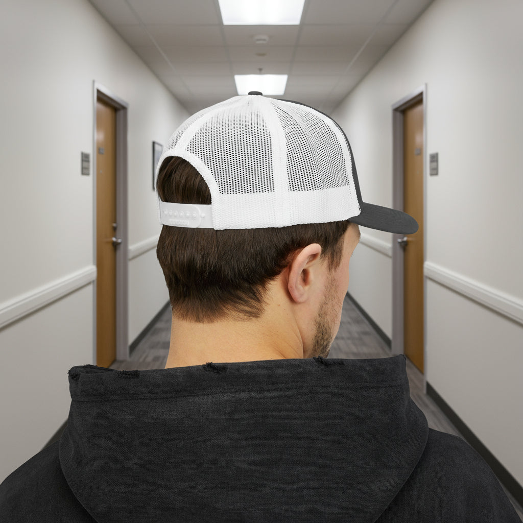 Person wearing a white and black cap and black hoodie walking down a hallway.
