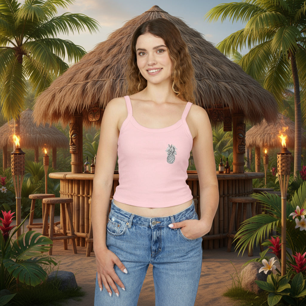 Woman wearing a pink tank top with a pineapple design and blue jeans in a tropical setting with huts and palm trees.