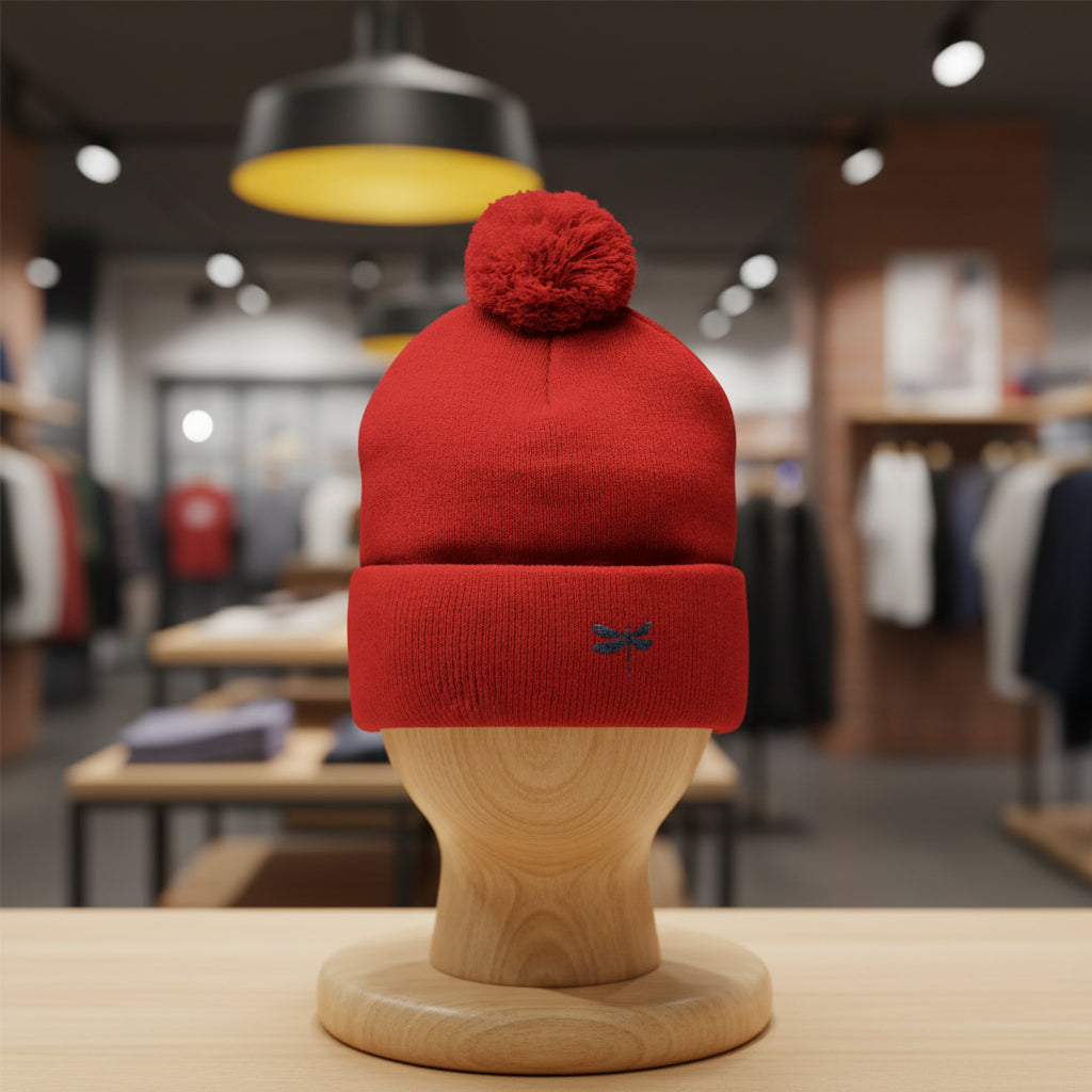 Red beanie with pom-pom on a wooden mannequin head in a store setting