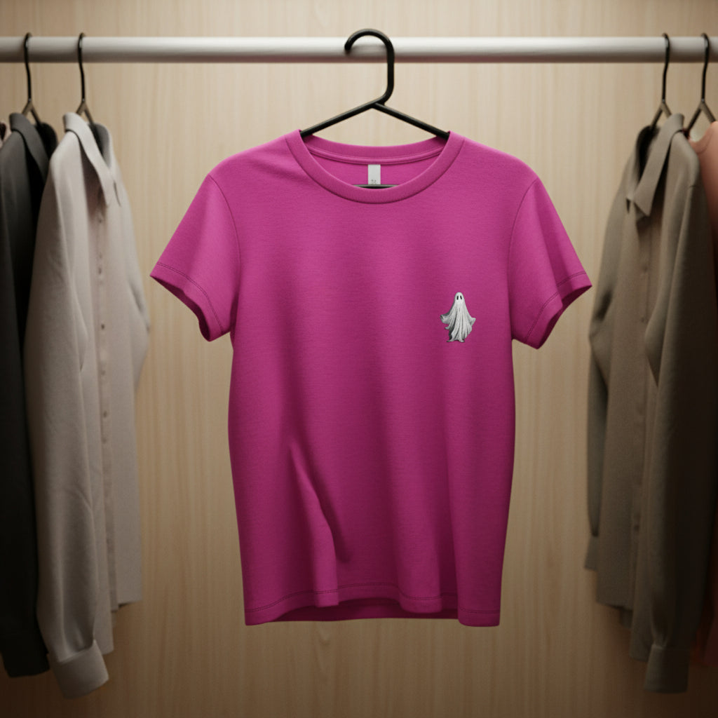 Pink t-shirt with a ghost design on a hanger against a wooden wardrobe background