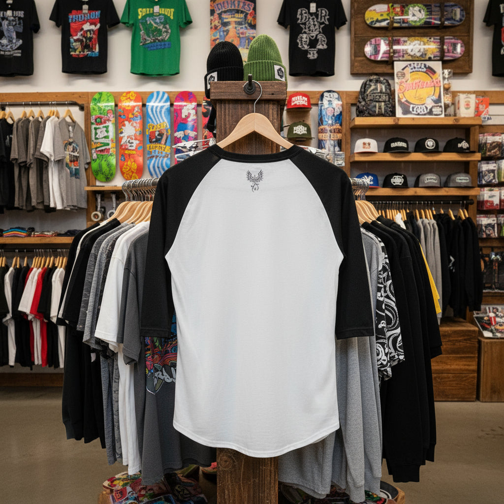 Black and white baseball shirt on a hanger in a store with clothing and skateboards in the background