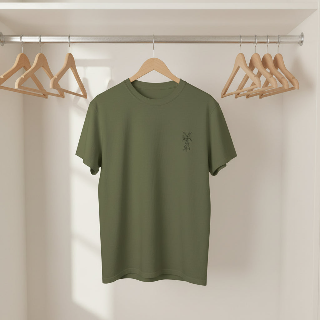 Green t-shirt with a small logo on a wooden hanger against a neutral background