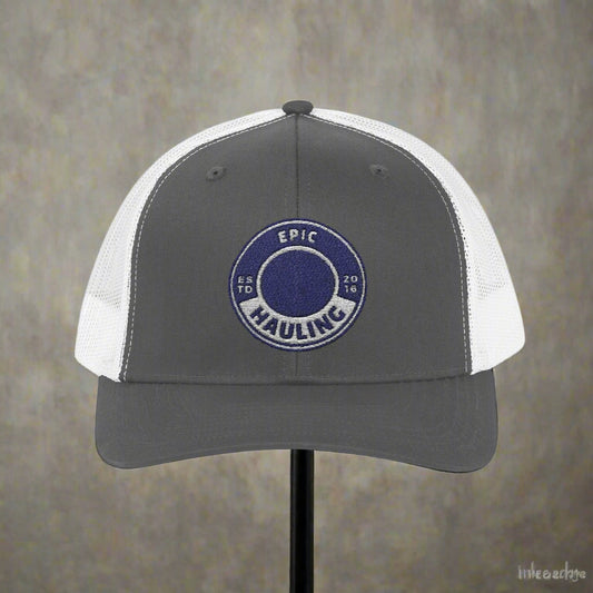 Gray and white cap with a blue circular logo on a gray background