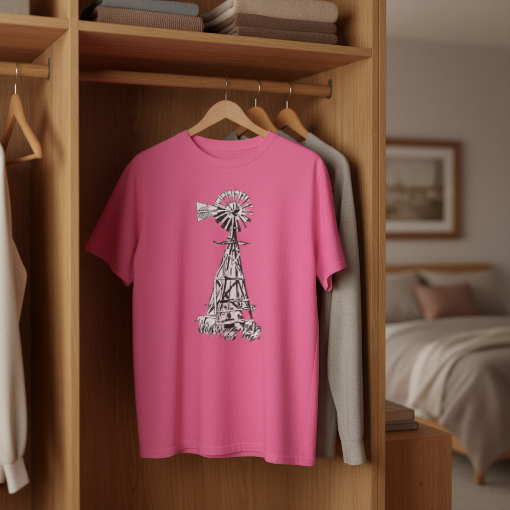 Pink t-shirt with a windmill design hanging in a closet.