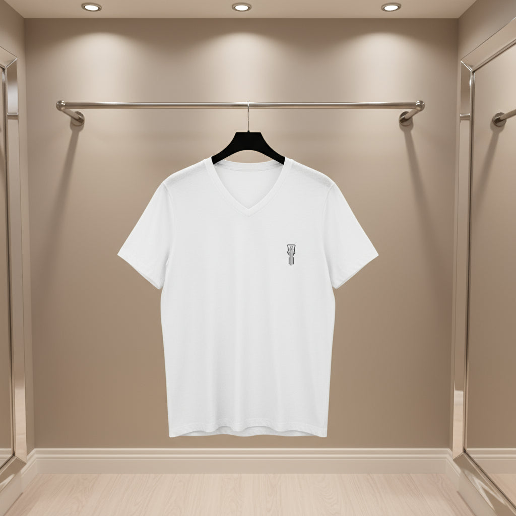 White t-shirt with a small logo on a hanger against a beige wall.