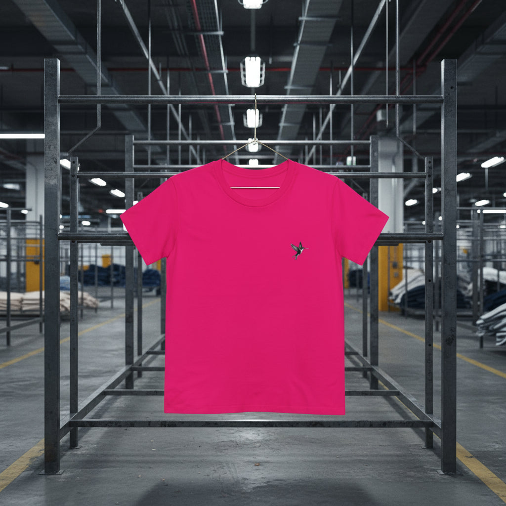 Pink t-shirt with a small design on a hanger in an industrial setting