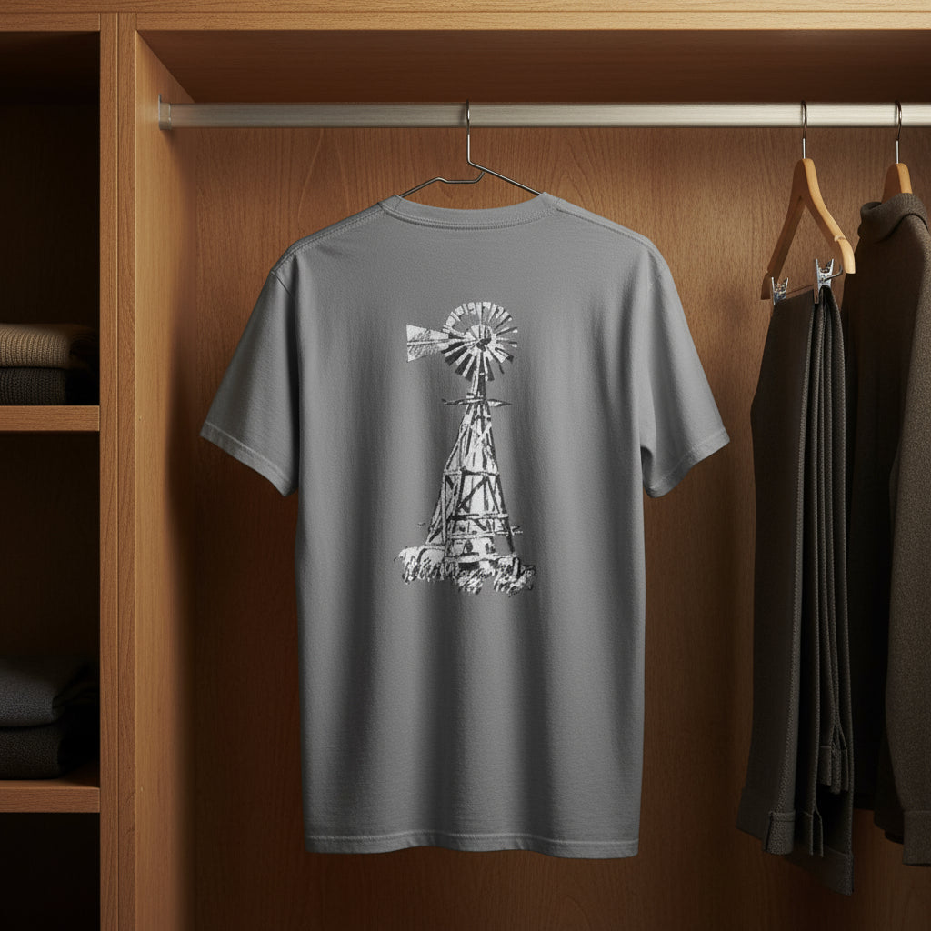 Gray t-shirt with a windmill design hanging in a wardrobe.
