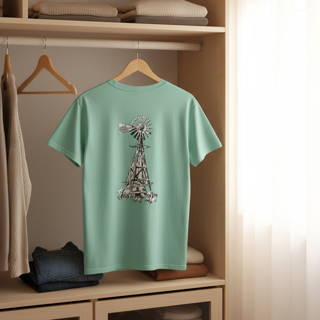 Mint green t-shirt with a graphic design on a wooden hanger against a neutral background.