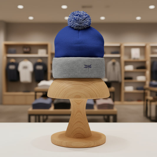 Two beanies stacked on a wooden stand with a blurred store background