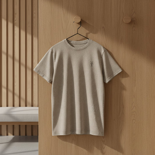 Beige t-shirt hanging on a wooden wall with a minimalistic design.