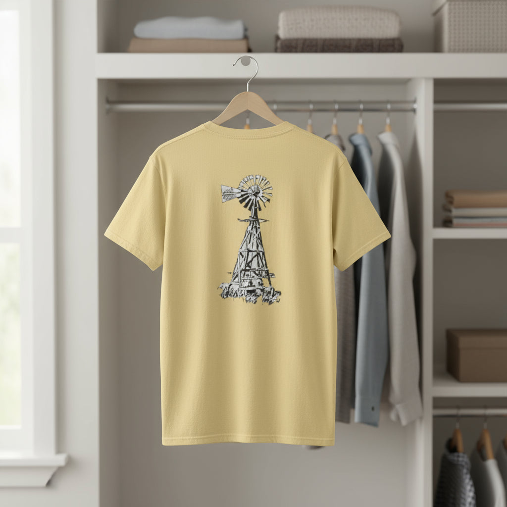 Yellow t-shirt with a windmill design on a hanger in a room.